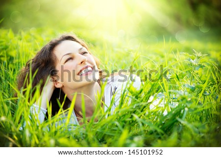 Beautiful Young Woman Outdoors. Enjoy Nature. Healthy Smiling Girl in Green Grass.