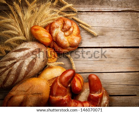 Bakery Bread on a Wooden Table. Various Bread and Sheaf of Wheat Ears over Wood Background.