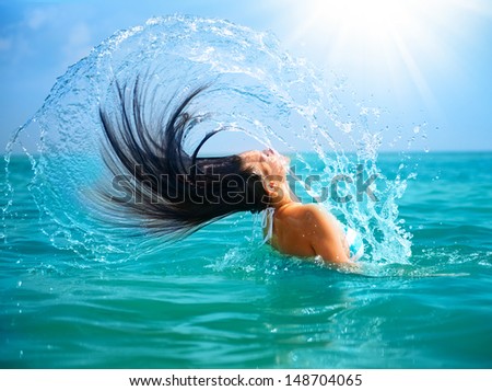 Beauty Model Girl Splashing Water with her Hair in the ocean. Beautiful Woman in Water