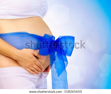 Pregnant Woman Belly with Blue Ribbon and Big Bow. Expecting Baby Boy. Pregnancy Concept