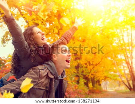 Happy Couple in Autumn Park. Fall. Young Family Having Fun Outdoors. Yellow Trees and Leaves. Laughing Man and Woman outside. Freedom Concept.