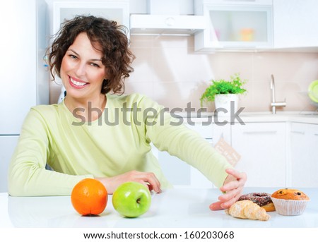 Diet. Dieting concept. Healthy Food. Beautiful Young Woman choosing between Fruits and Sweets. Weight Loss