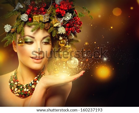 Christmas Winter Woman with Miracle in Her Hand. Fairy. Beautiful New Year and Christmas Tree Holiday Hairstyle and Make up. Magic. Beauty Fashion Model Girl over Holiday Blinking Background.