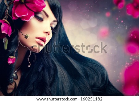 Beauty Woman With Long Black Hair. Beauty Brunette Model Girl Portrait With Big Purple Flowers In Her Hair. Hairstyle, Perfect Face Make Up. Smoky Eyes Shadows
