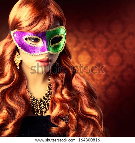 Masquerade. Beautiful Girl in a Carnival mask. Beauty Glamorous Woman Celebrating. Holiday Make up and Hairstyle. Long Red Wavy Hair