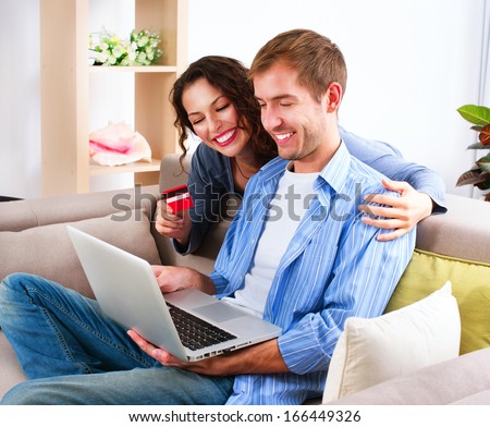 Online Shopping. Happy Smiling Couple Using Credit Card to Internet Shop. Young Family with laptop and credit card buying online. Christmas and New Year Gifts. e-shopping