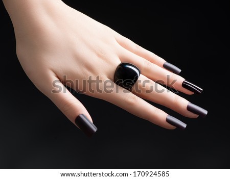 Manicured Nail With Black Matte Nail Polish. Fashion Manicure. Long Nails With Dark Nailpolish Isolated On Black Background. Salon. Nail Art. Black Ring