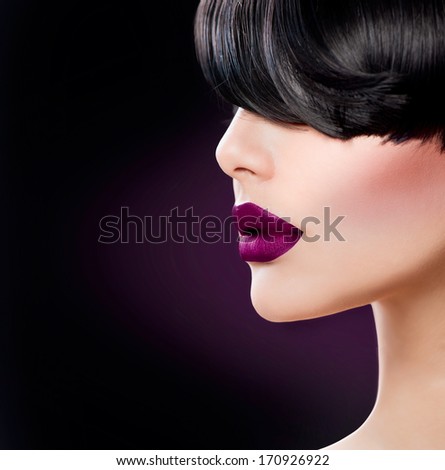 Beauty Woman Face close up with Beautiful Dark Violet Lips and Black Hair. Fringe Hairstyle. Perfect Skin. Trendy Matte Violet Lipstick. Model Face. Sensual Lips Closeup. Makeup.