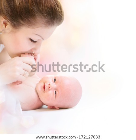 Mother and her Newborn Baby. Happy Mother and Baby kissing and hugging. High key soft image of Beautiful Family. Maternity concept. Parenthood. Motherhood