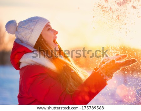 Beauty Winter Girl Blowing Snow In Frosty Winter Park. Outdoors. Flying Snowflakes. Sunny Day. Backlit. Beauty Young Woman Having Fun In Winter Park. Good Mood