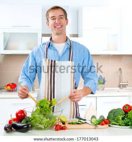 Young Man Cooking in the kitchen. Healthy Food - Vegetable Salad. Diet. Dieting Concept. Healthy Lifestyle. Cooking At Home. Prepare Food