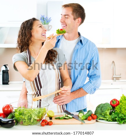 Cooking. Happy Couple Cooking Together - Man and Woman in their Kitchen at home Preparing Vegetable Salad. Diet. Dieting. Healthy Food