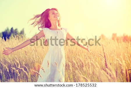 Beauty Girl Outdoors enjoying nature. Beautiful Teenage Model girl in white dress running on the Spring Field, Sun Light. Glow Sun. Free Happy Woman. Toned in warm colors.