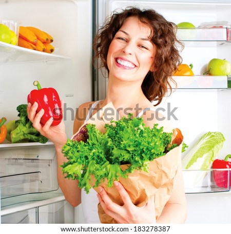 Healthy Eating Concept. Diet. Beautiful Young Woman near the Fridge  with healthy food. Fruits and Vegetables in the Refrigerator. Vegan food