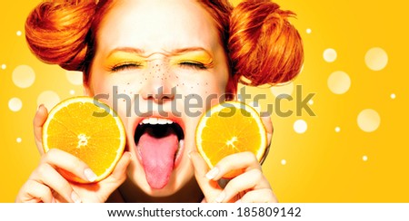 Beauty Model Girl with Juicy Oranges. Beautiful Joyful teen girl with freckles, funny red hairstyle and yellow makeup. Open mouth. Professional make up. Orange  Slices