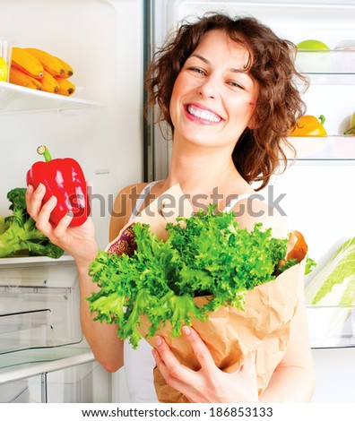Healthy Eating Concept. Diet. Beautiful Young Woman near the Fridge with healthy food. Fruits and Vegetables in the Refrigerator. Vegan food