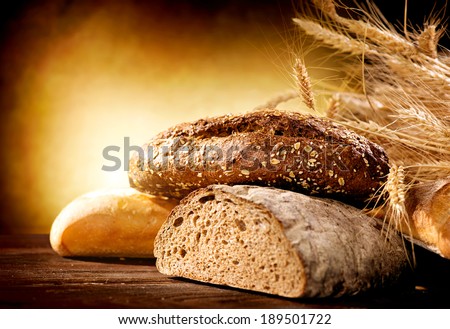Bakery Bread on a Wooden Table. Various Bread and Sheaf of Wheat Ears Still-life.