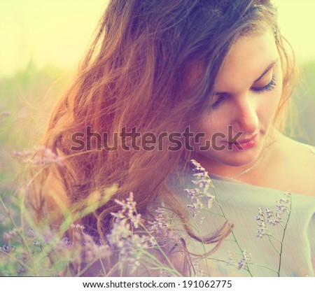 Beauty Romantic Girl Portrait. Sensual Woman Lying on a Meadow with Violet Flowers. Beautiful Woman Enjoying Nature. Romantic beauty in fantasy lavender field