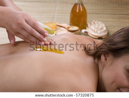 Spa.Young woman getting a massage.Pouring Massage Oil