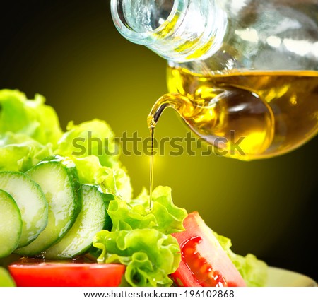 Healthy Vegetable Salad with Olive oil dressing. Pouring Olive oil. Healthy vegetarian food. Vegan. Diet, dieting concept. Lettuce, tomatoes, cucumbers. Organic bio food.