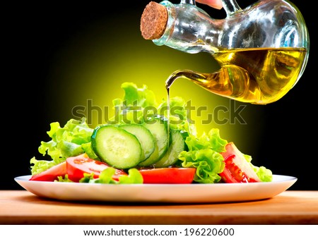 Healthy Vegetable Salad with Olive oil dressing. Pouring Olive oil. Healthy vegetarian food. Vegan. Diet, dieting concept. Lettuce, tomatoes, cucumbers. Organic bio food.