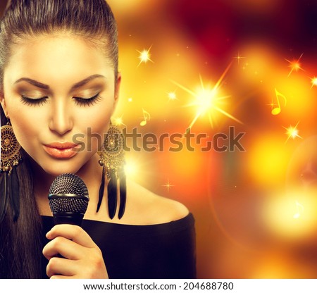 Beautiful Singing Girl. Beauty Woman with Microphone over Blinking bokeh golden night background. Glamour Model Singer. Karaoke song