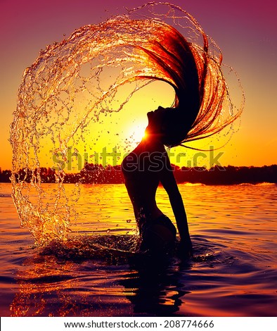 Beauty Model Girl Splashing Water with her Hair. Teen girl Swimming and splashing on summer beach over sunset. Beautiful Woman in Water