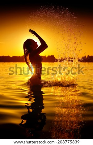 Beauty Model Girl Splashing Water. Teen girl Swimming and splashing on summer beach over sunset. Beautiful Woman Enjoying nature