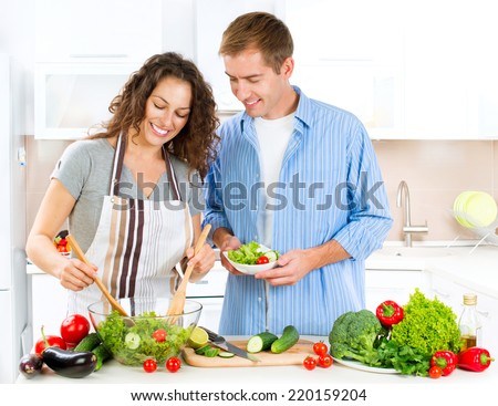 Happy Couple Cooking Together - Man and Woman in their Kitchen at home Preparing Dinner - Vegetable Salad. Diet. Dieting. Healthy vegetarian food, vegan. Family cooking together at home