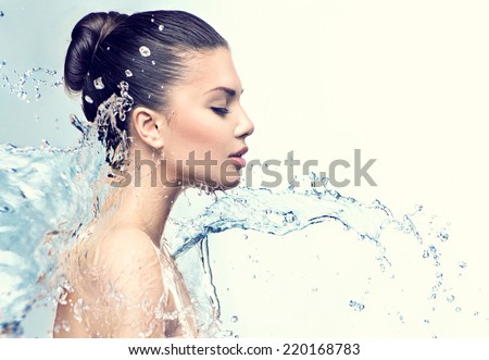 Beautiful Model Woman with splashes of water in her hands. Beautiful Smiling girl under splash of water with fresh skin over blue background. Skin care, Cleansing and moisturizing concept. Beauty face