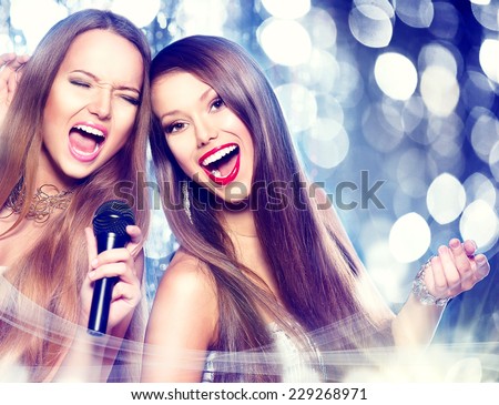 Karaoke party. Beauty girls with a microphone singing and dancing over holiday blinking background. Disco party. Celebration