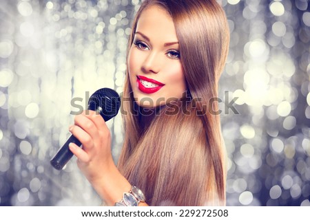 Singing Woman. Beautiful model Girl Singing. Beauty gorgeous lady with Microphone over holiday glowing Background. Singer. Karaoke song, party