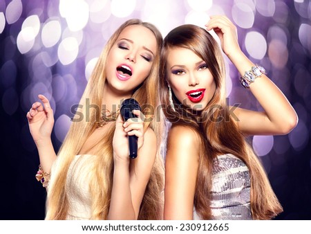 Karaoke party. Beauty girls with a microphone singing and dancing over holiday blinking background. Disco party. Celebration