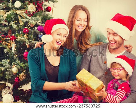 Christmas Family with Kids opening Christmas gifts. Happy Smiling Parents and Children at Home Celebrating New Year. Christmas Tree. Christmas scene