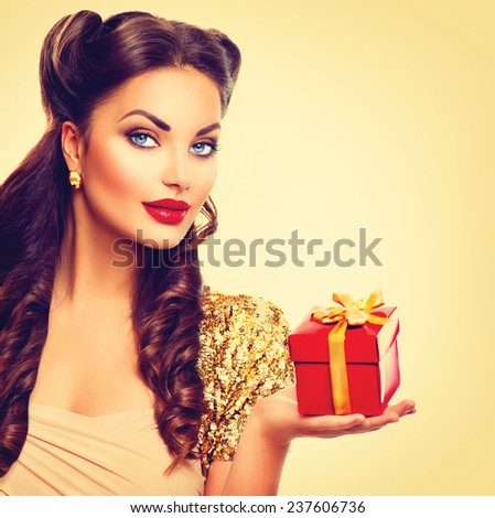 Beauty Pin up girl with holiday gift box in her hand. Retro woman portrait. Vintage styled make up and hairstyle. Pinup style lady