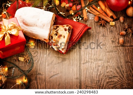 New year table. Christmas food border design. Stollen. Traditional Sweet Fruit Loaf. Xmas holiday table setting, decorated with garlands, baubles, walnuts, hazelnuts, cinnamon sticks.