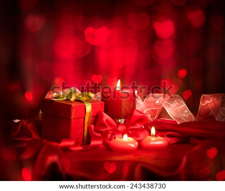 Valentine\'s Day. Valentine Red Heart shaped candles and Gift on Red Silk over glowing background. Beautiful Valentine card art design