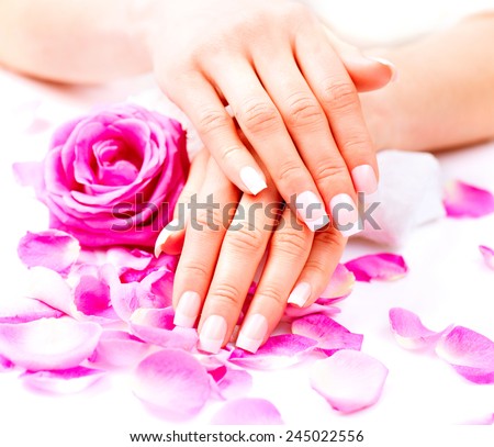 Manicure, Hands spa. Beautiful female hands, soft skin, beautiful nails with pink rose flowers petals. Healthy Woman hands. Beauty salon. Treatment. Beautiful woman\'s nails with french manicure