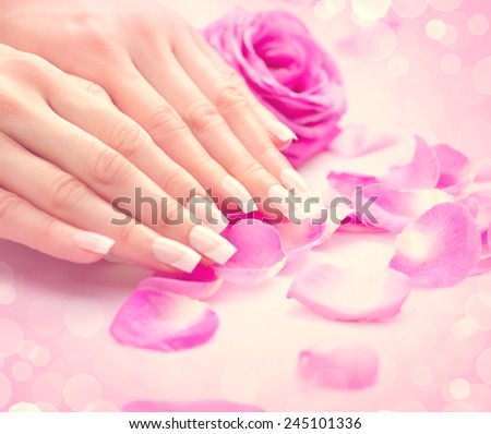 Manicure, Hands spa Beautiful feamle hands, soft skin, beautiful nails with pink rose flowers petals. Healthy Woman hands. Beauty salon. Beauty treatment. Beautiful nails with french manicure