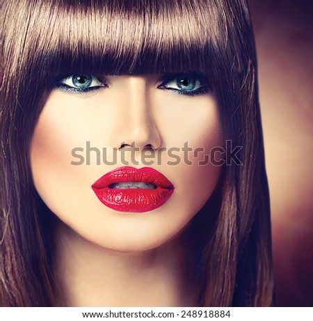 Beautiful brunette woman with fashion fringe haircut and professional makeup. Red lips, smooth brown hair