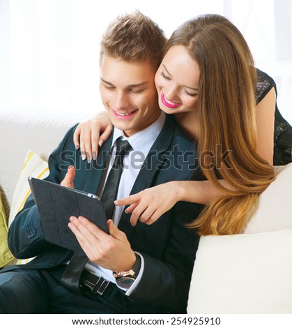 Online Shopping. Happy Smiling Couple Using PC Tablet at home. Internet Shop on-line. Young couple with pc computer chatting or buying online. Touchscreen. e-shopping