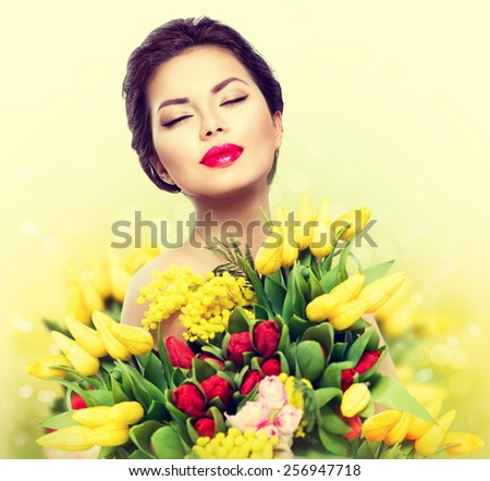 Beauty model Woman with Spring Flower bouquet. Beautiful girl with a Bouquet of colorful Tulip flowers. Happy surprised model woman smelling flowers. Mother\'s Day. Springtime