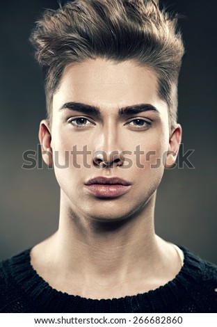 Handsome young fashion model man portrait. Attractive Guy face closeup. Vogue style image of elegant young man with stylish hairstyle