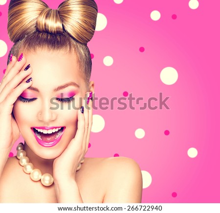Beauty fashion happy model girl with funny bow hairstyle, pink nail art and makeup over polka dots background. Laughing retro styled young woman