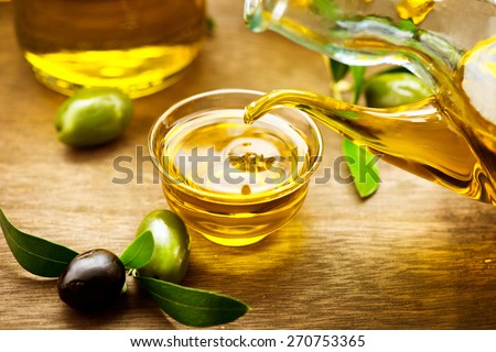 Olive Oil. Bottle pouring Virgin Olive Oil in a bowl close up. Olives and Healthy Olive oil being poured from glass bottle. Diet. Dieting concept. Healthy food