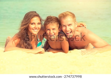 Happy Young Family with Little Kid Having Fun at the Beach. Joyful Family. Travel and Vacation. Summer Vacations. Seaside