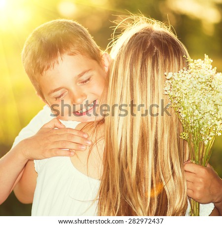 Mother and her little son with bouquet of flowers outdoors, Happy family mom and kid kissing and hugging. Mother\'s day gift.