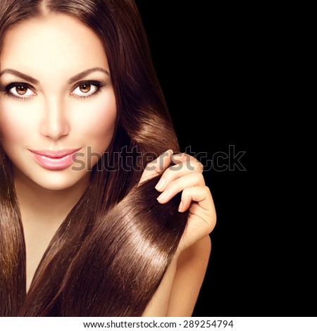 Beauty Model girl with Healthy Brown Hair. Beautiful brunette woman touching long smooth shiny straight hair. Hairstyle. Hair cosmetics, haircare. Hair care, extensions. Isolated on black background