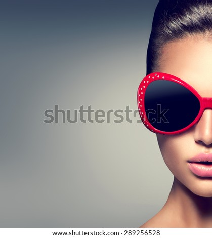 Beauty Fashion model brunette girl wearing stylish sunglasses. Beautiful Lady face. Sexy woman portrait over dark background