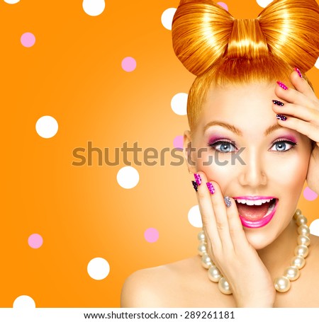 Beauty fashion surprised happy model girl with funny bow hairstyle, red hair, pink nail art and makeup over polka dots orange background. Laughing retro styled young woman